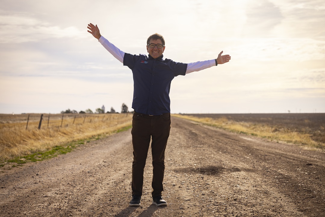 Man with hands in air, sun shining from behind.