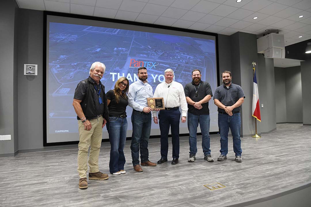 Men and women standing together with an award plaque. 