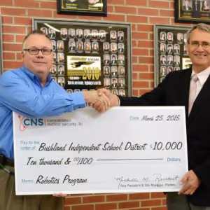 Joe Papp, CNS Director of Mission Engineering, presents the $10,000 donation to Don Wood, Bushland ISD Superintendent, to kick off the district's robotics program.