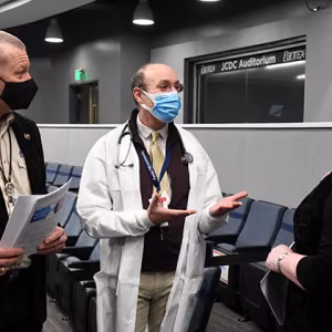 Dr. Paston (center) talks to Geoff Beausoleil, manager of the NNSA Production Office, and Michelle Reichert, CNS president and chief executive officer, at the vaccination clinic.