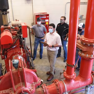 Pantex summer intern Drew Rowlands (center) checks a pump station system with coworkers Jonathan Burkhead (left), Ronnie Anderle (black shirt), and Colton Mooney (right).